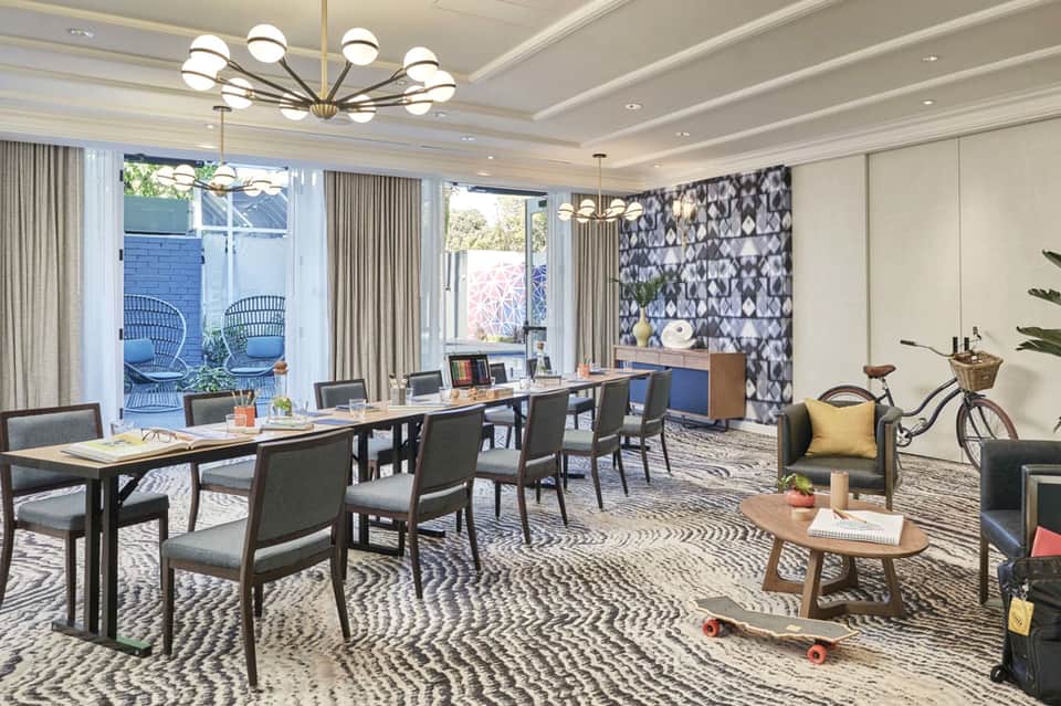 Modern office space with wooden desks, patterned accent wall, and outdoor patio access