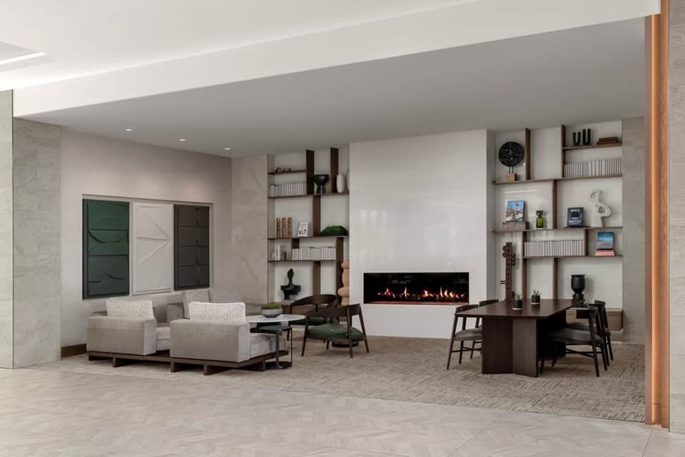 Contemporary hotel lobby with fireplace, floating shelves, cream armchairs, and modern furnishings