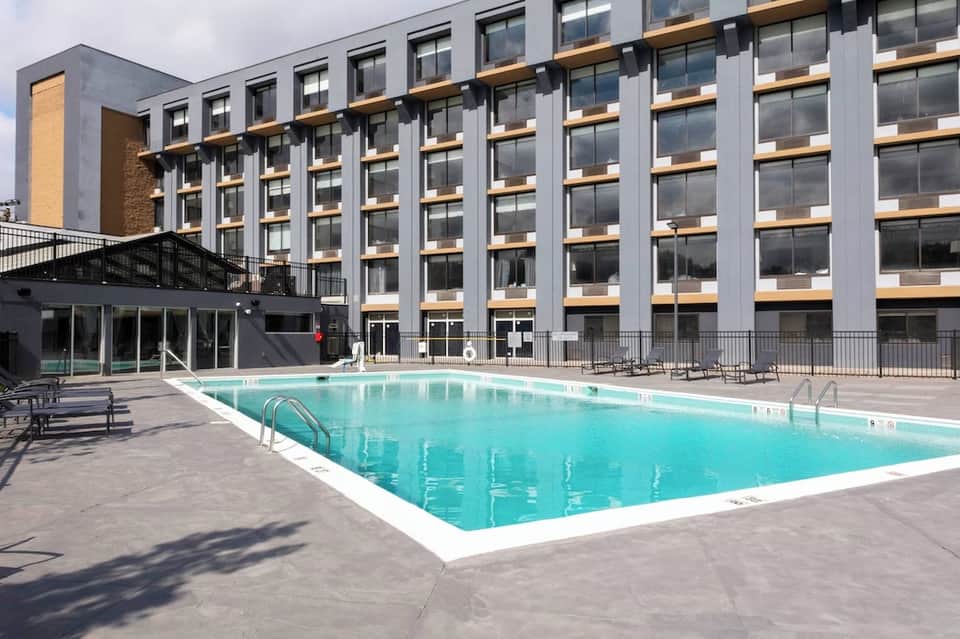 Resort outdoor swimming pool with modern multi-story hotel building behind it
