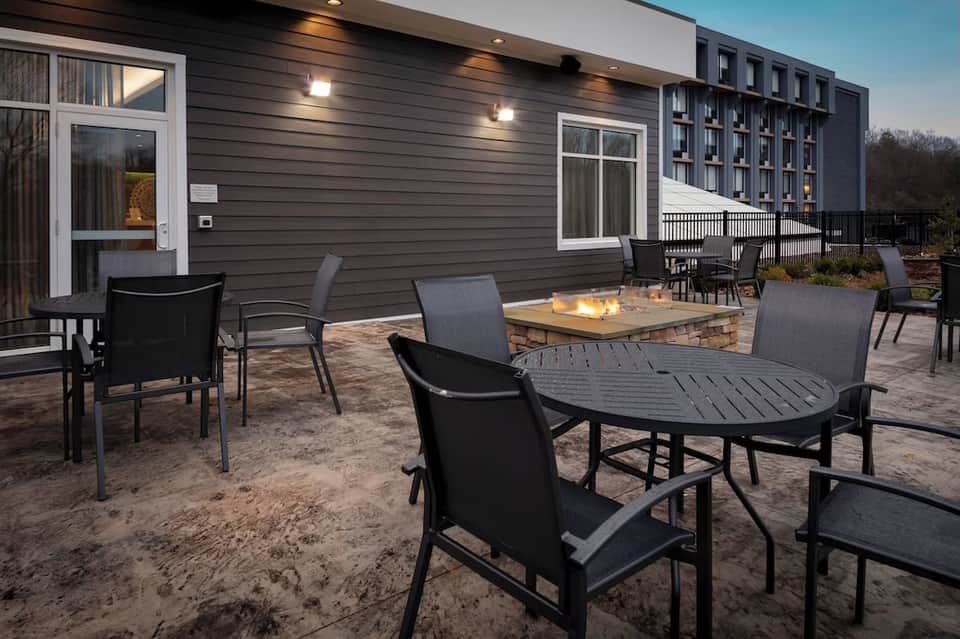 Outdoor patio with fire table, modern seating, and resort building backdrop