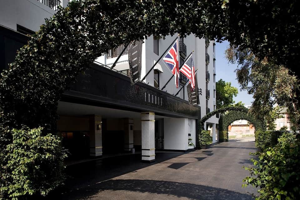 Historic hotel entrance with ivy-covered façade, British and American flags, columns, and ivy-lined courtyard