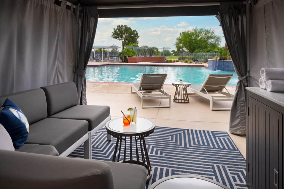 Luxury cabana with gray furniture overlooking turquoise resort pool