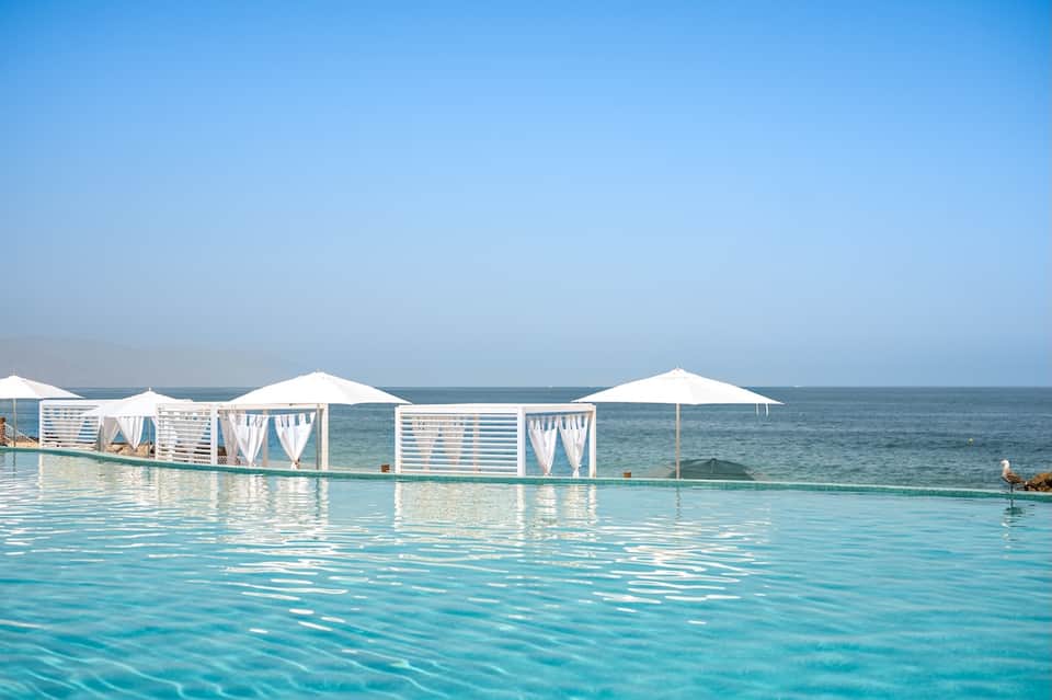 Infinity pool with white cabanas and ocean horizon blending seamlessly together