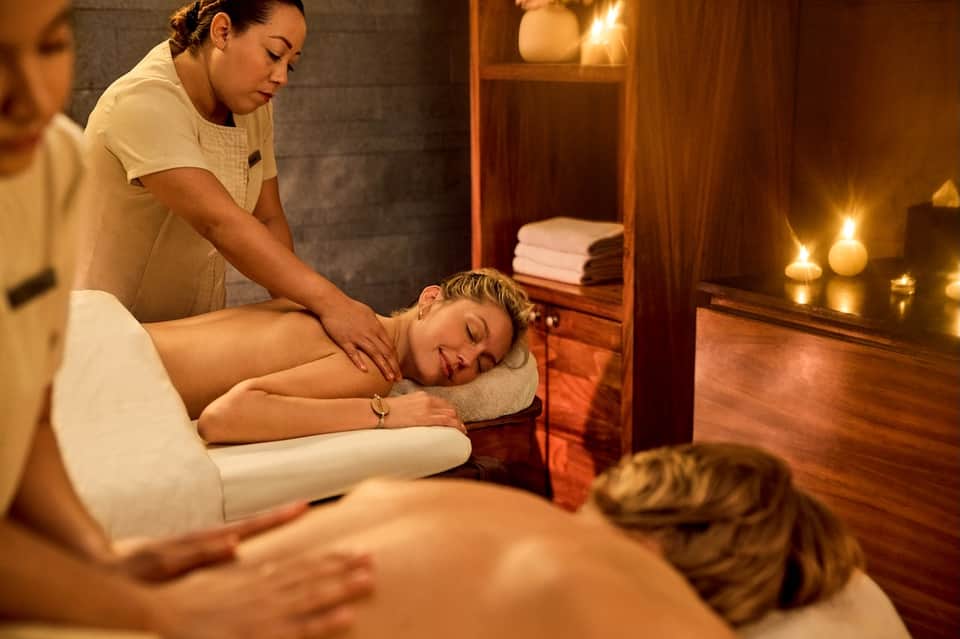 Spa massage therapist performing a relaxation massage on a client in a candlelit room