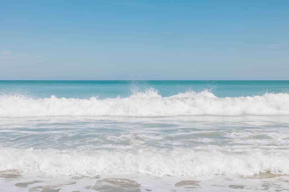 Scenic turquoise ocean waves with white sandy beach under clear blue sky
