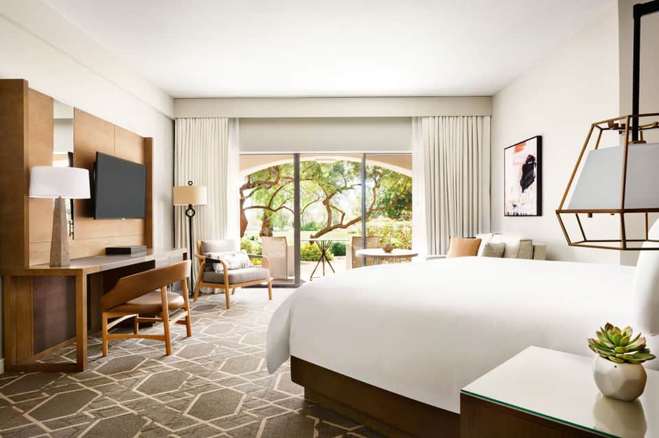 Luxury hotel bedroom with king bed, wood furnishings, sliding glass doors to terrace garden