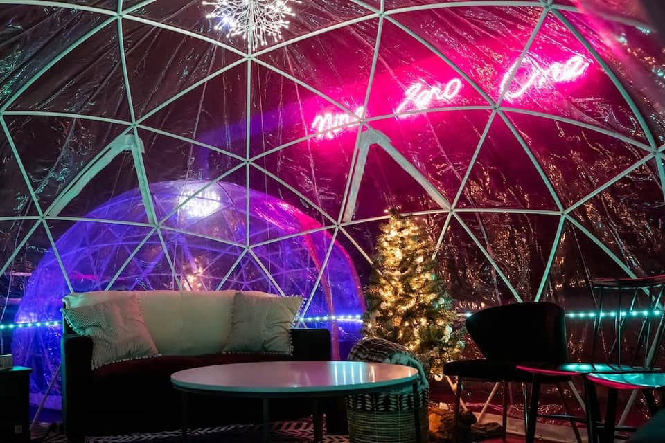 Illuminated geodesic dome interior with vibrant neon lighting and modern seating areas