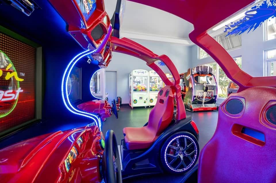 Colorful arcade game room with neon signs, racing simulators, and bright red and blue lighting