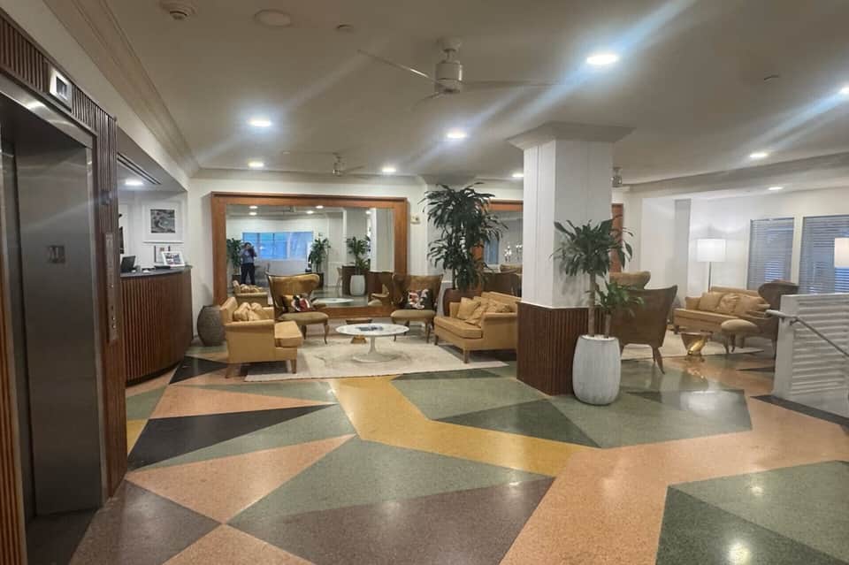 Spacious hotel lobby with geometric floor patterns, tan seating areas, and modern furnishings