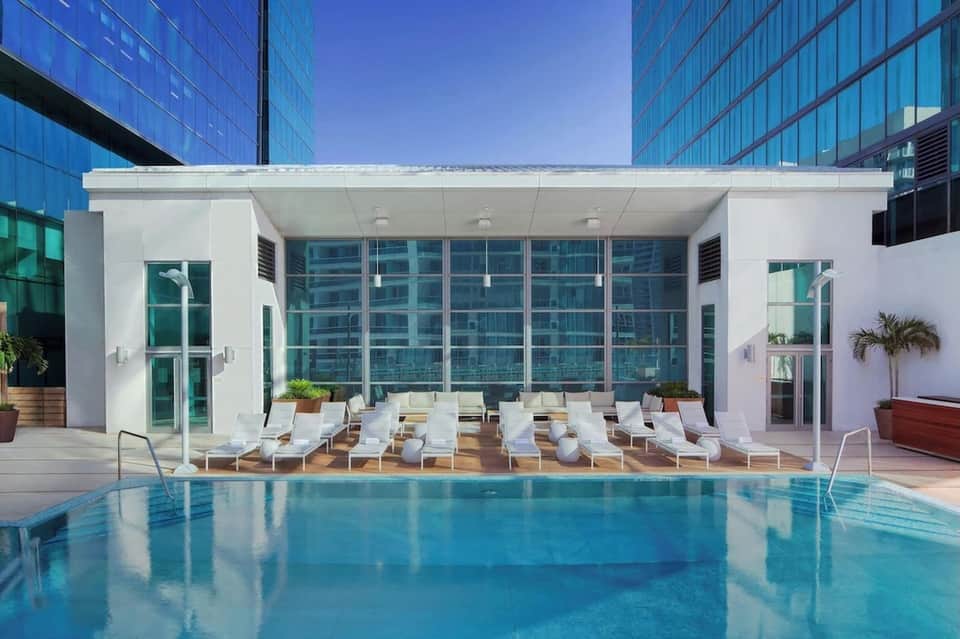 Modern indoor heated pool with white lounge chairs and floor-to-ceiling windows