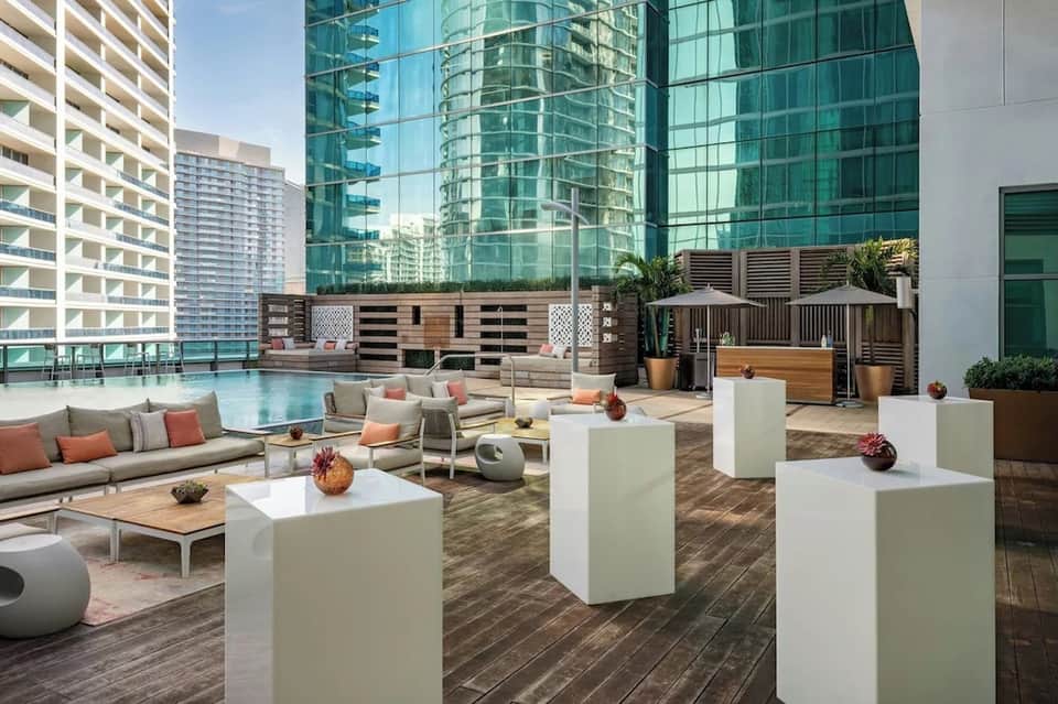 Rooftop lounge with modern seating, fire pit, and skyline view surrounded by high-rise buildings