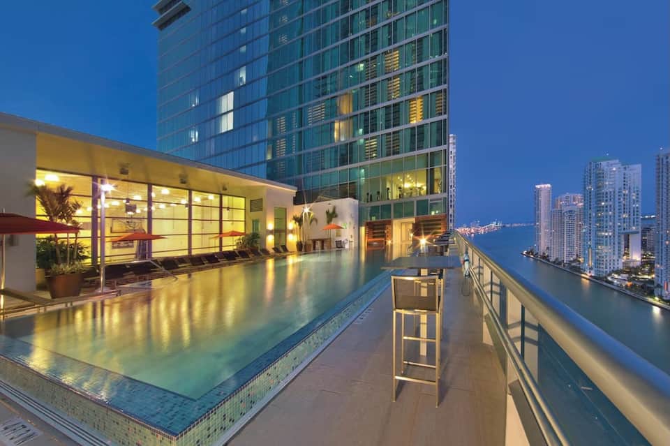 Rooftop infinity pool at night overlooking illuminated city skyline and waterfront