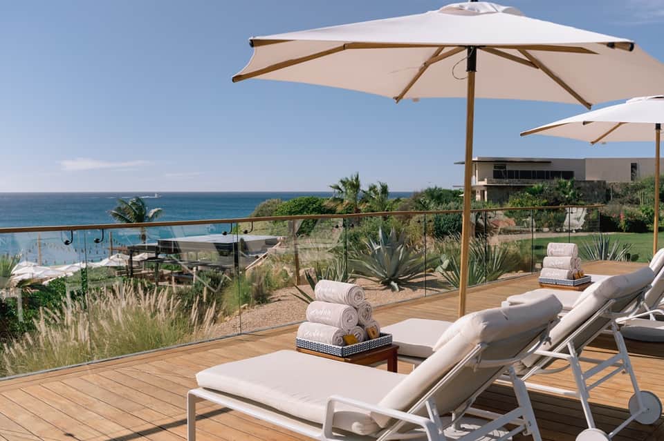 Oceanfront terrace with lounge chairs, umbrellas, and ocean view from wooden deck