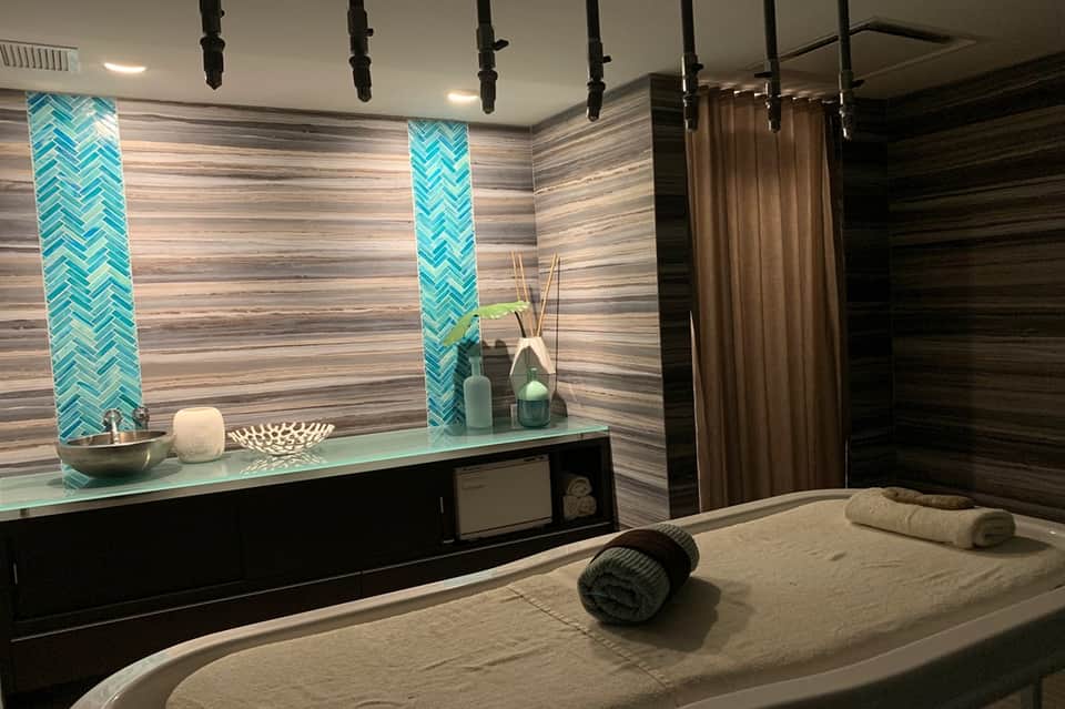 Modern spa massage room with turquoise tile accents, treatment bed, and mood lighting