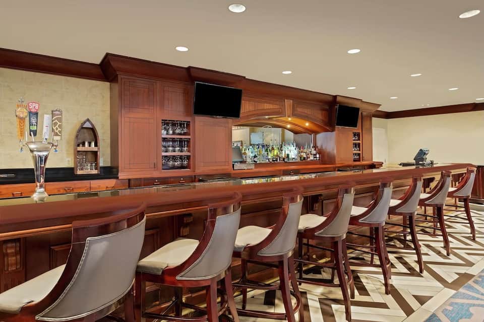 Upscale wooden bar with extensive liquor selection, bar seating, and polished mahogany countertop