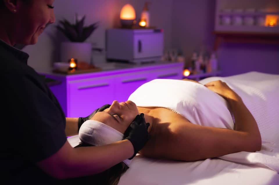 Spa massage treatment in purple-lit room with therapist providing professional service