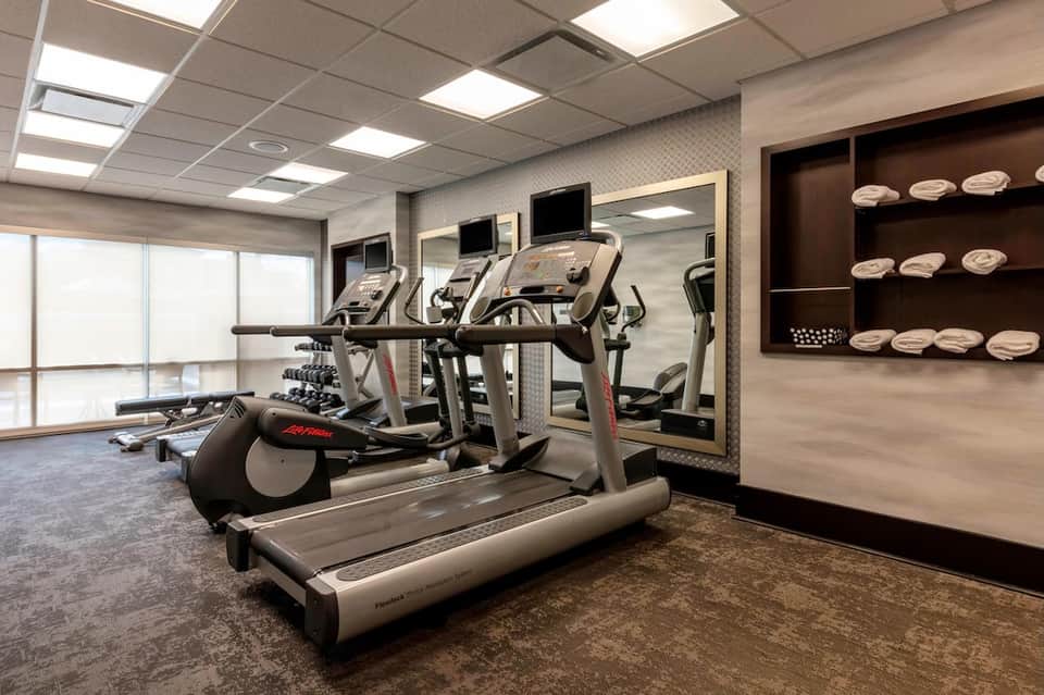 Fitness center with cardio equipment, treadmill, exercise bike, and wall mirror