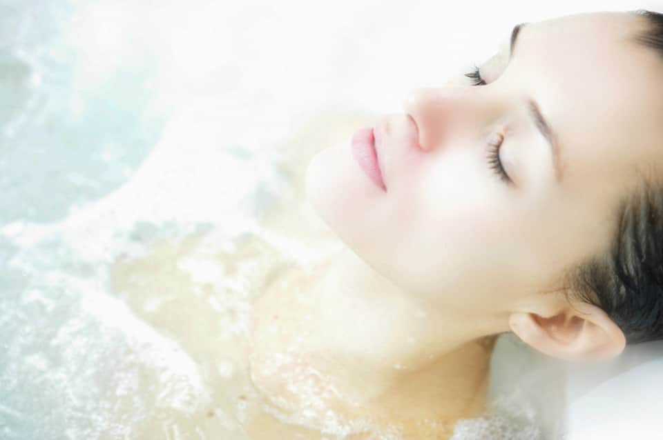 Woman relaxing in thermal hot spring with mineral-rich water and serene expression