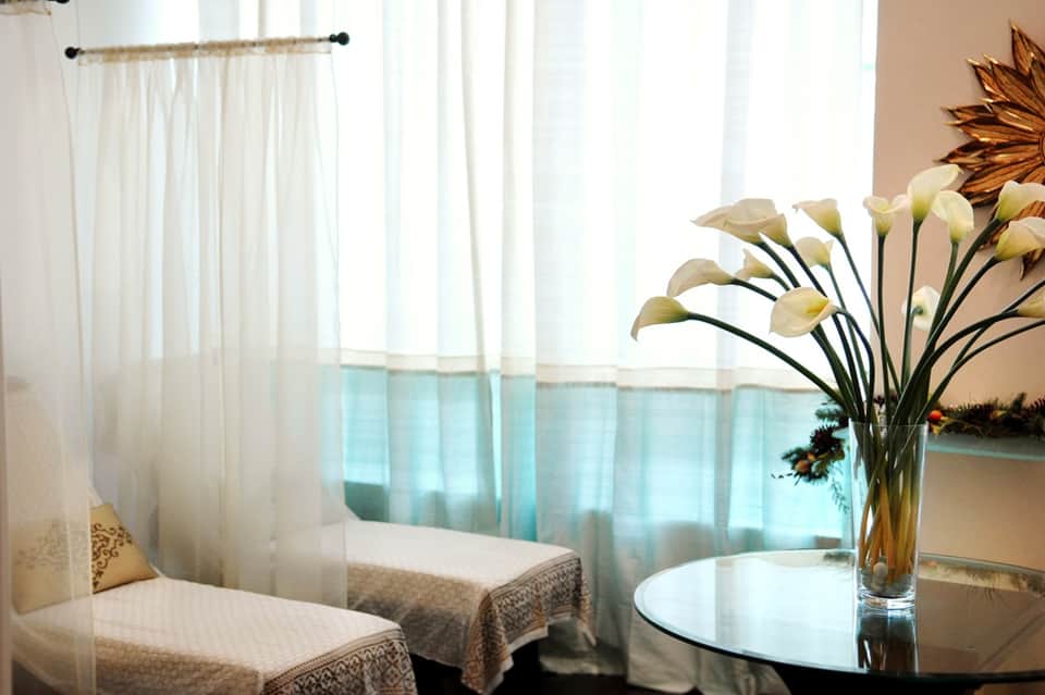 Elegant hotel room interior with twin beds, sheer curtains, and water view