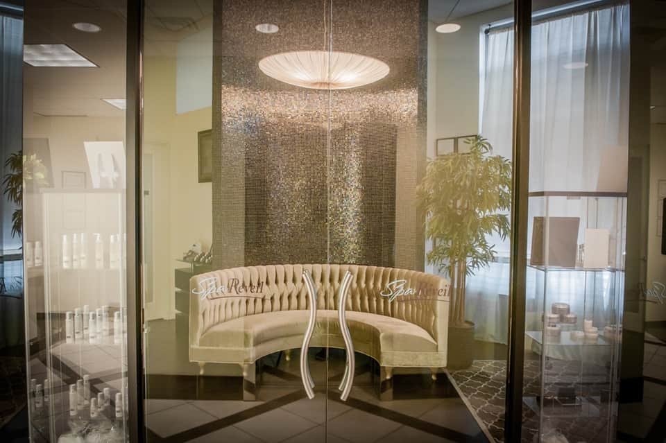 Spa reception area with curved cream seating, mosaic tile walls, and glass entrance doors