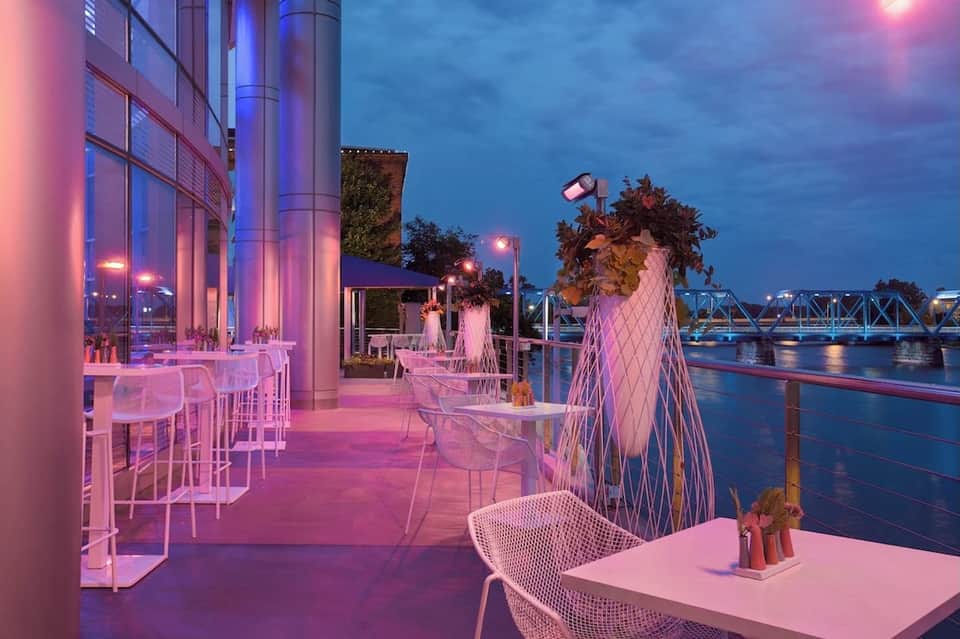 Waterfront bar and lounge with pink lighting, modern seating, and river bridge views