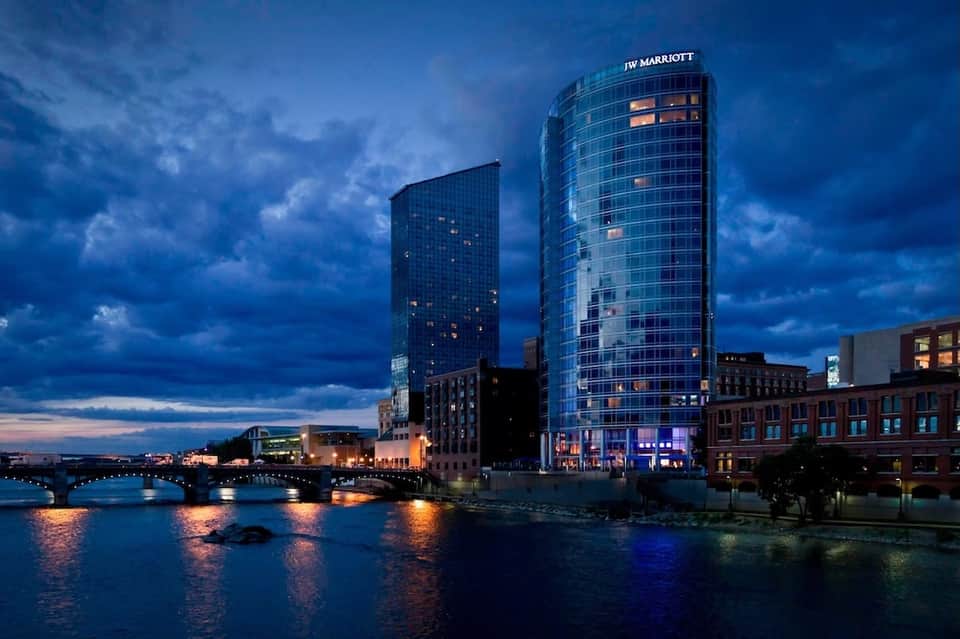 JW Marriott hotel tower illuminated at dusk along waterfront with bridge and city lights in background