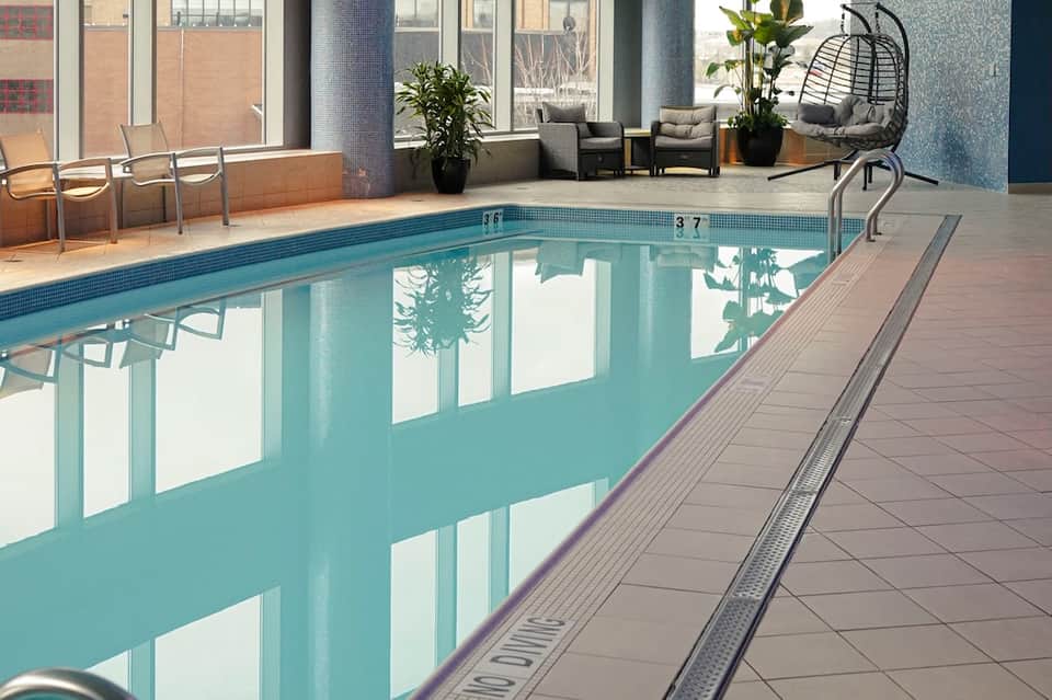 Indoor heated pool with lounge seating area, floor-to-ceiling windows, and modern amenities