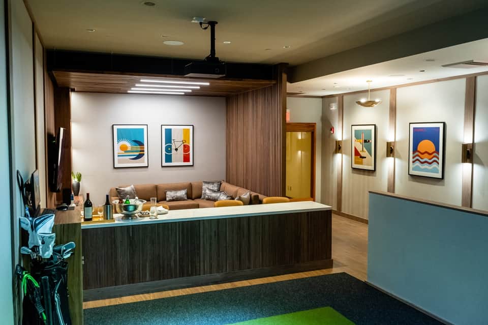 Modern hotel reception desk with colorful artwork, wood paneling, and welcoming lounge area