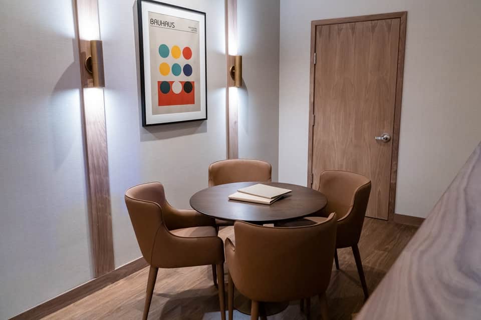 Small meeting room with round table, brown leather chairs, wood door, and Bauhaus artwork