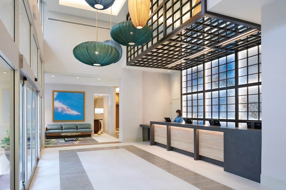 Modern hotel lobby with geometric pendant lights, sitting area, and reception desk