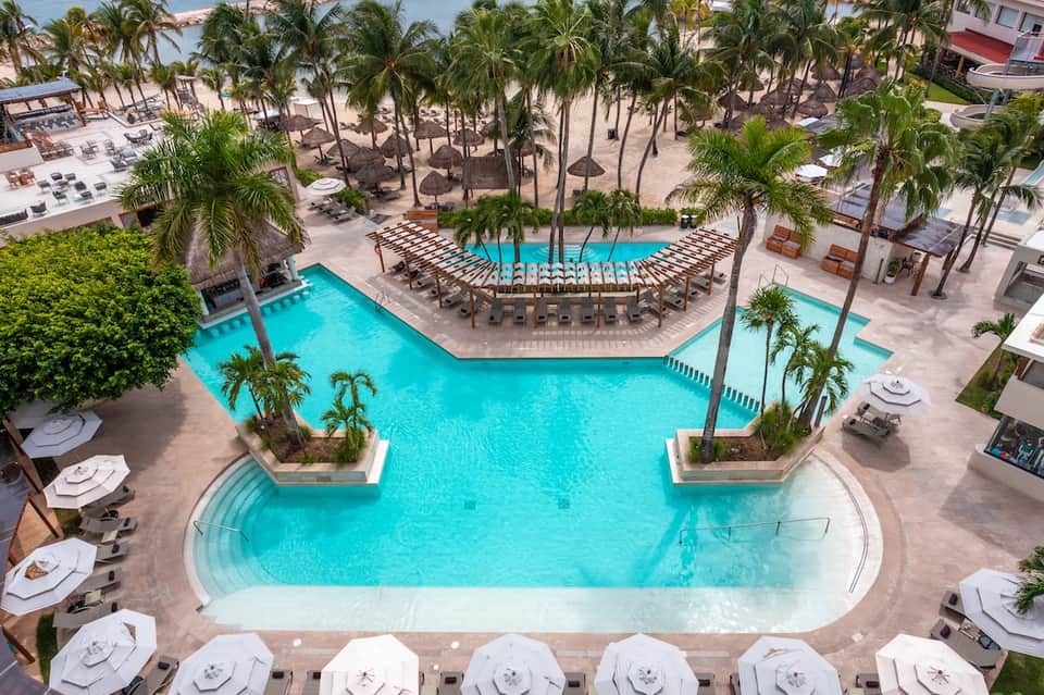 Aerial view of large resort pool complex with palm trees and cabanas