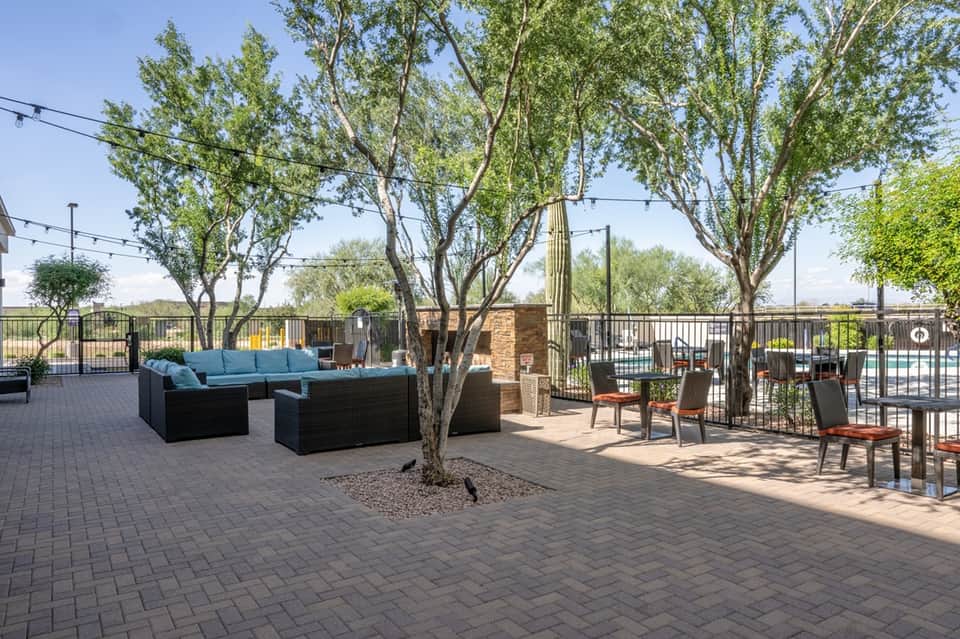 Rooftop patio with turquoise lounge seating, mature trees, and city views beyond railing