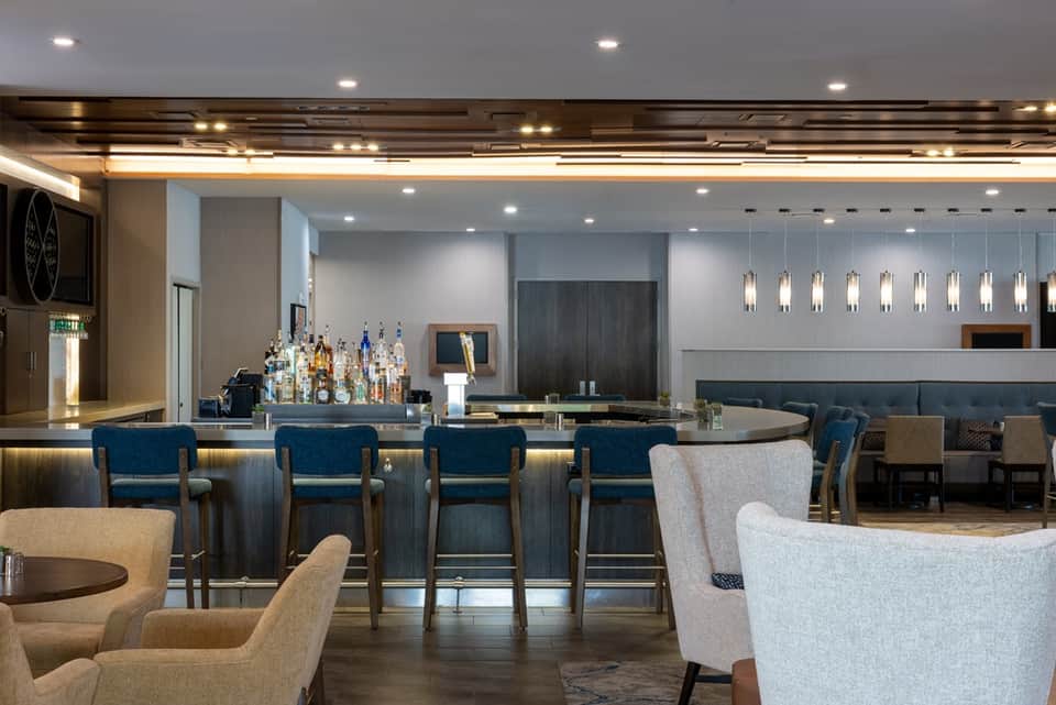 Modern hotel bar and lounge with blue bar stools, ambient lighting, and upscale furnishings