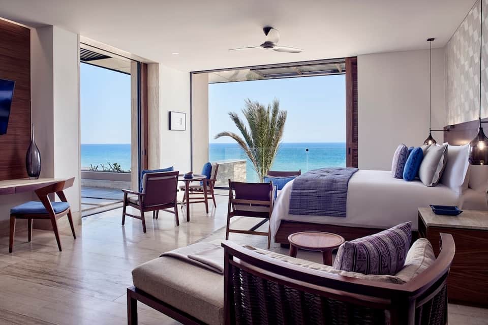 Luxury oceanfront resort bedroom with floor-to-ceiling windows, sea view, modern furnishings, and balcony