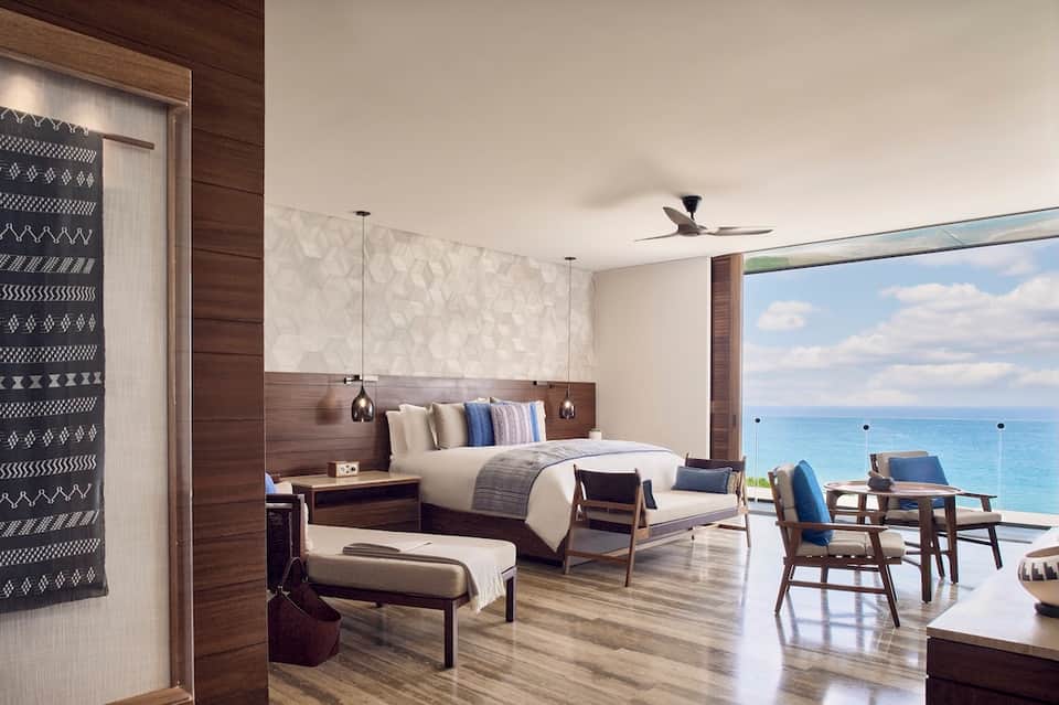 Luxury oceanfront bedroom with king bed, ocean views, wooden accents, and contemporary coastal design