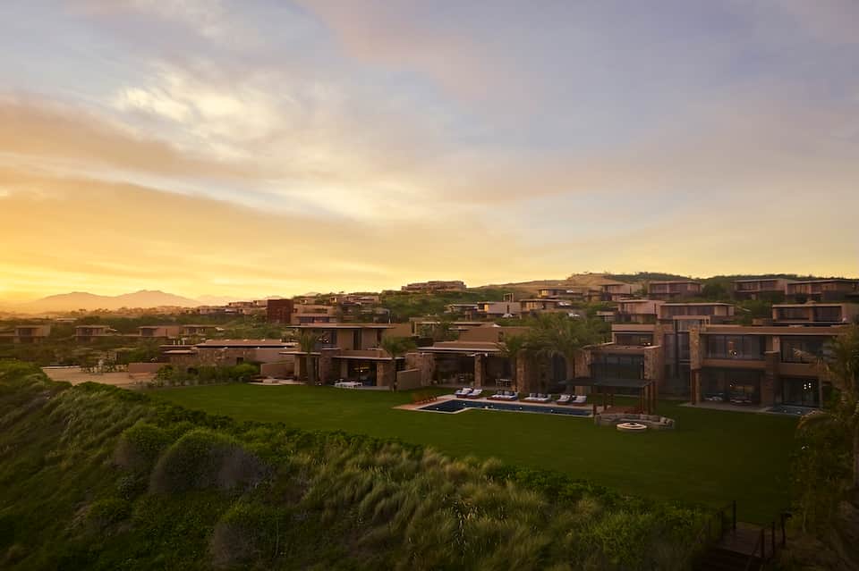 Sunset aerial view of luxury residential resort community with pools and homes on hillside landscape