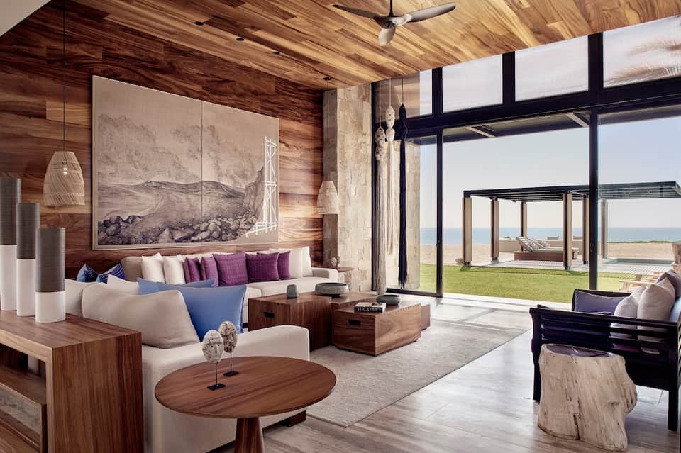 Modern waterfront lounge with wood accents, curved seating, large windows, and panoramic coastal views