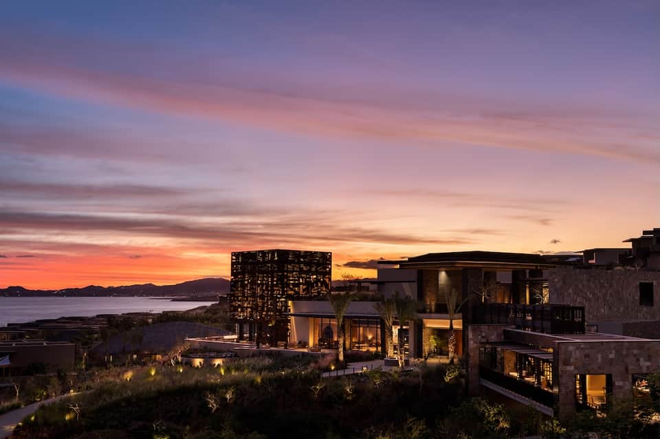 Modern hillside resort at dusk with ocean views and illuminated architecture