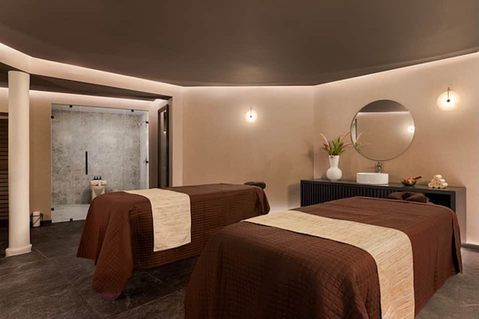 Twin massage beds in spa treatment room with brown quilted linens and modern minimalist design