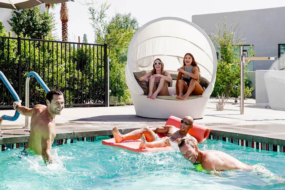 Family enjoying modern pool with spherical shade pod, lounge floats, and contemporary architecture