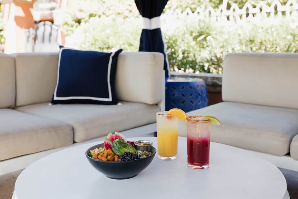 Outdoor lounge seating with fresh fruit bowl and colorful cocktails on white coffee table