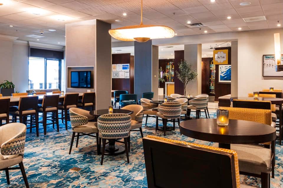 Upscale lounge with patterned armchairs, modern lighting fixtures, and contemporary decor in neutral tones