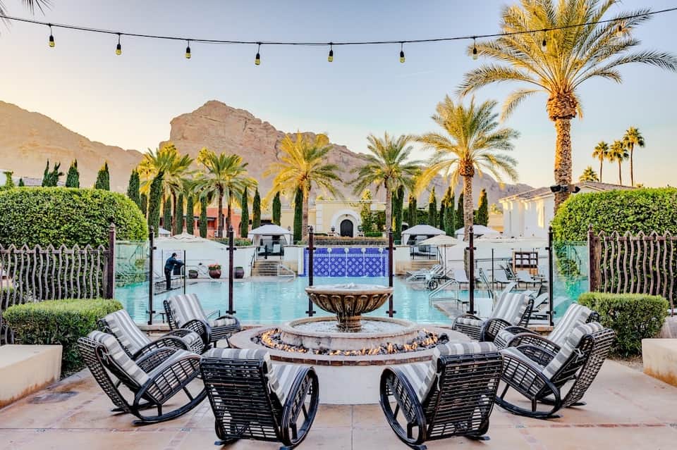 Resort pool with fire pit, rocking chairs, mountain backdrop, and string lighting