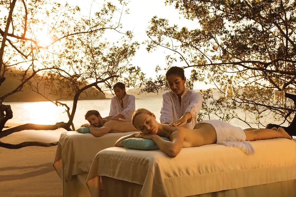 Beachfront spa massage treatment under mangrove trees with ocean view during golden hour