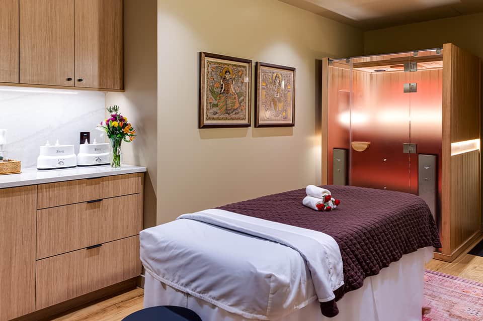 Spa treatment room with massage bed, wood cabinetry, and modern amenities