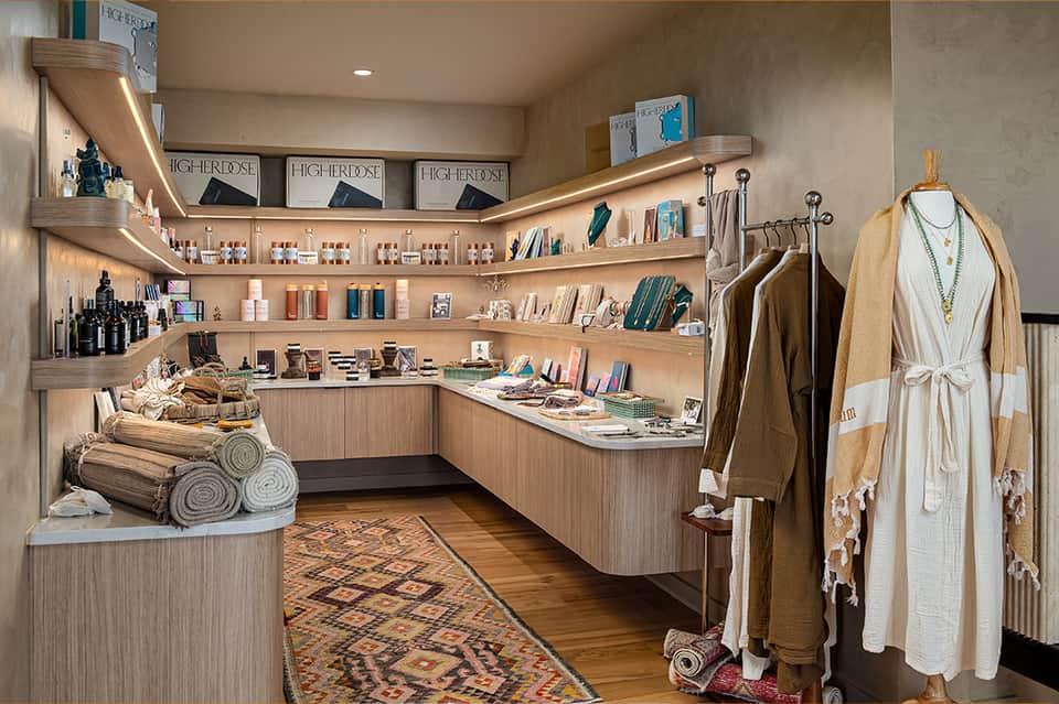 Upscale retail boutique with wooden shelving, beauty products, clothing display, and rolled towels