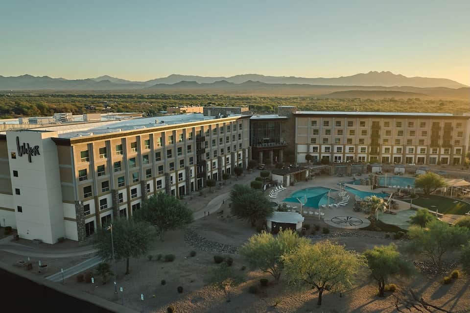 Modern hotel complex with pool area at sunset, desert landscape and mountains visible