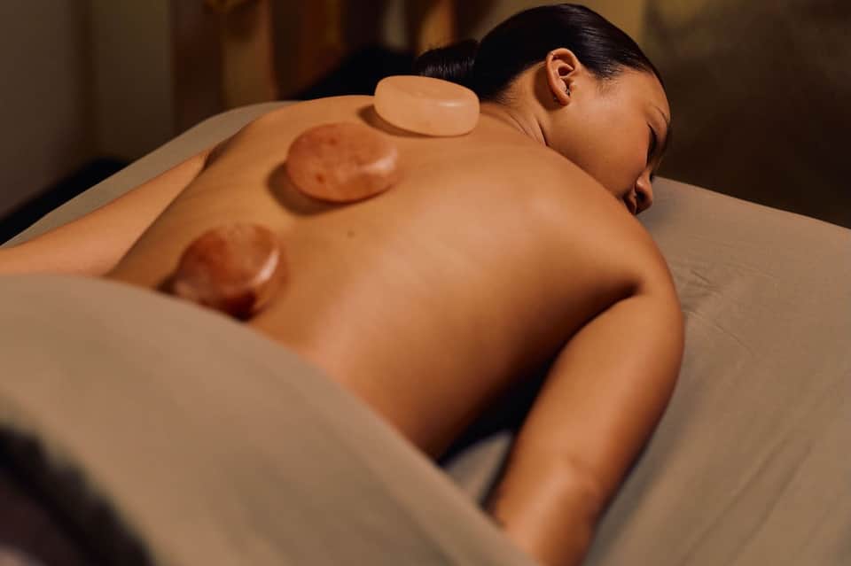 Woman relaxing during spa hot stone massage treatment on her back