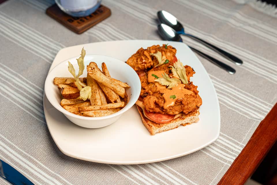 Plated fried chicken sandwich and fries served at restaurant table with place settings
