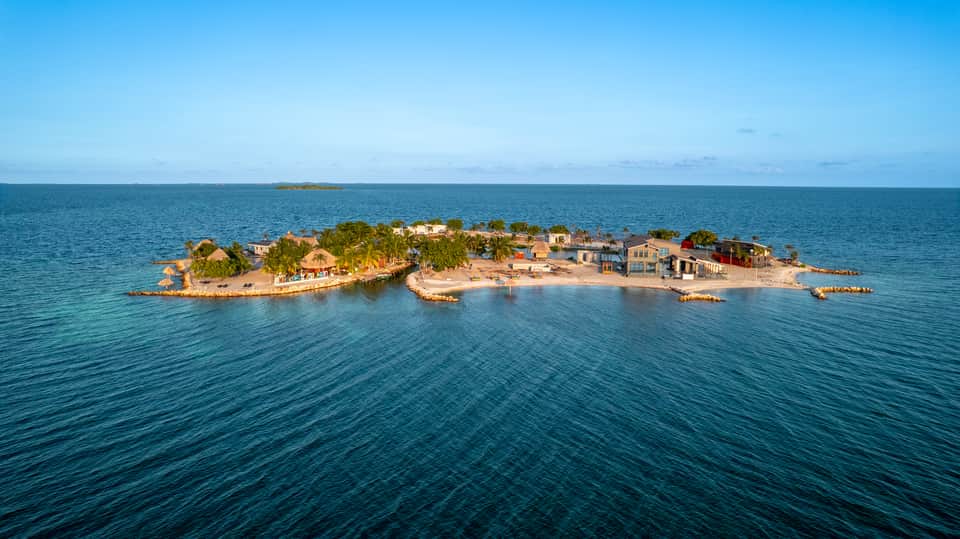 Small island resort surrounded by turquoise ocean water with palm trees and colorful buildings